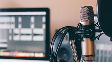 Professional podcast microphone beside an editing workstation