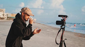 Content creator filming with a camera by the beach